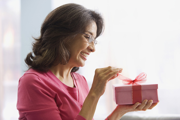 Hispanic woman opening gift